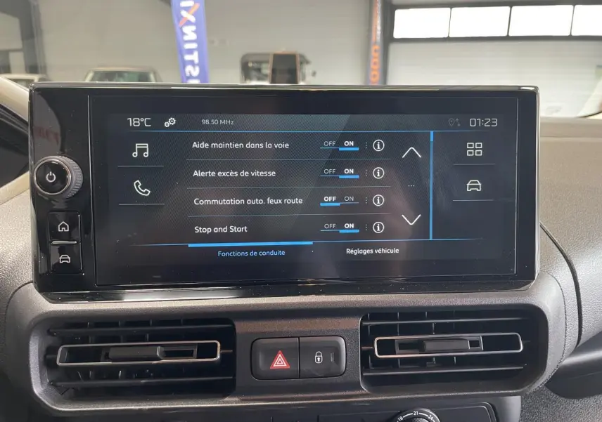 Écran tactile central du tableau de bord du Peugeot Partner blanc, affichant les aides à la conduite activées.