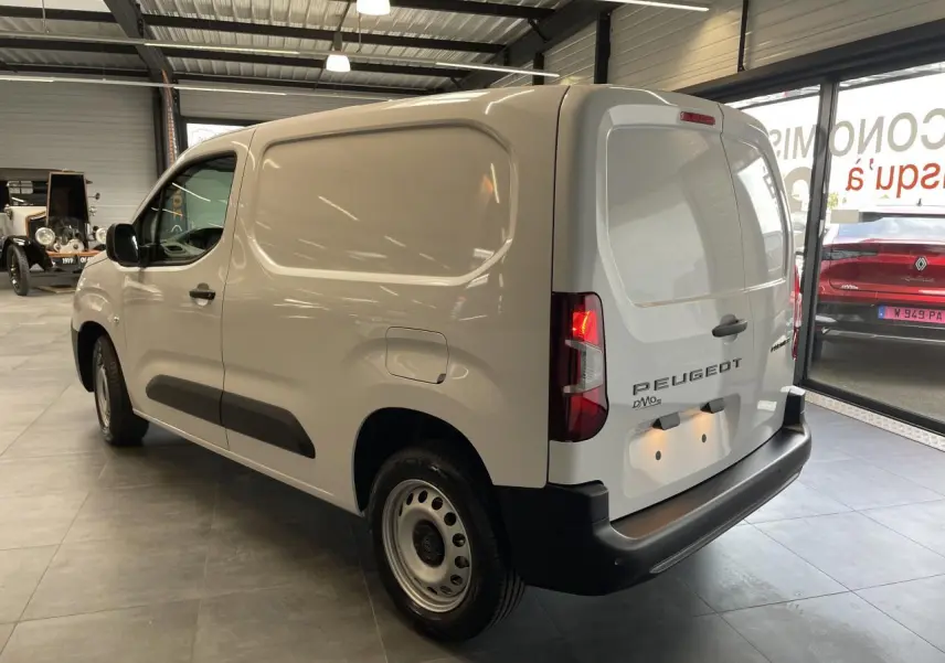 Vue 3/4 arrière droite du Peugeot Partner blanc, fourgon utilitaire avec portes arrière battantes et jantes tôles grises.