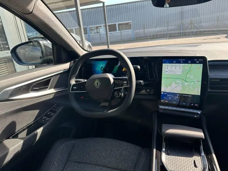 Vue intérieure côté conducteur du Renault Austral 2025, tableau de bord noir avec écran tactile vertical et volant multifonction.