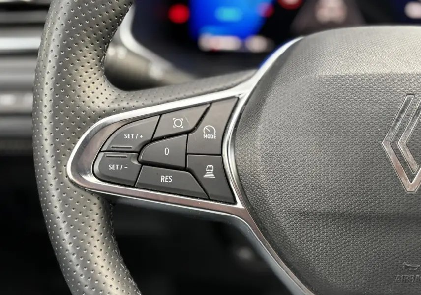 Gros plan sur le volant perforé avec commandes intégrées du Renault Symbioz, intérieur noir texturé.