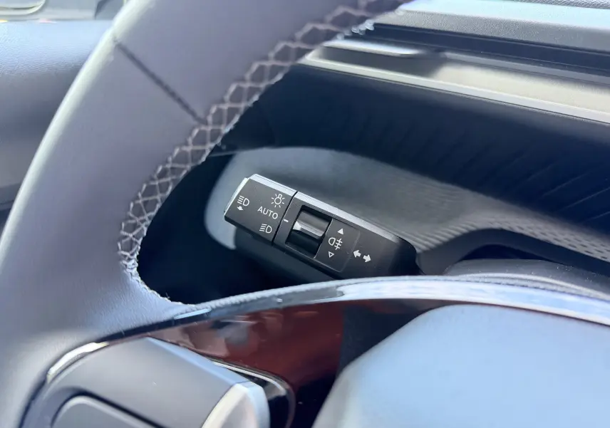 Gros plan sur la commande des feux et clignotants à gauche du volant dans l’habitacle gris du Citroën E-C3 2025.