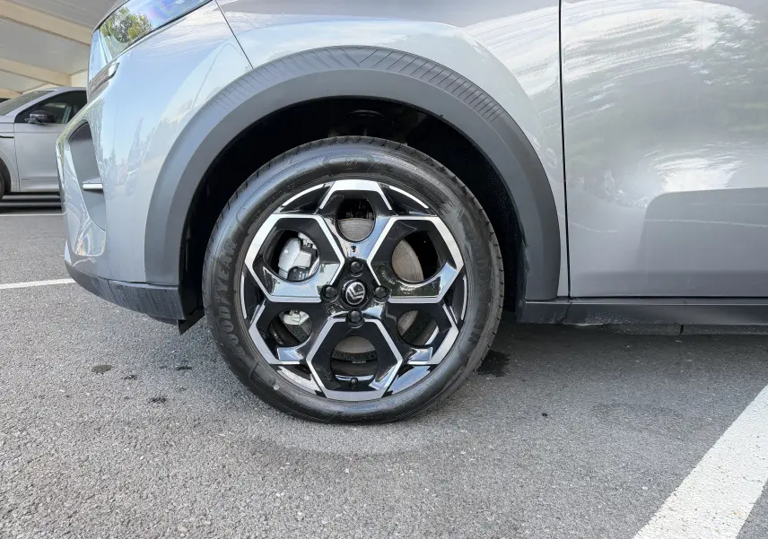 Gros plan sur la roue avant gauche de la Citroën E-C3 113 MAX gris Mercury avec jante alliage 17 pouces au design hexagonal.