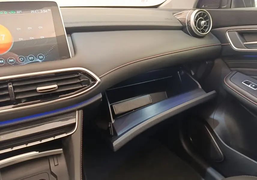 Intérieur côté passager du MG Motor EHS blanc 2023, tableau de bord noir avec boîte à gants ouverte et écran tactile visible.