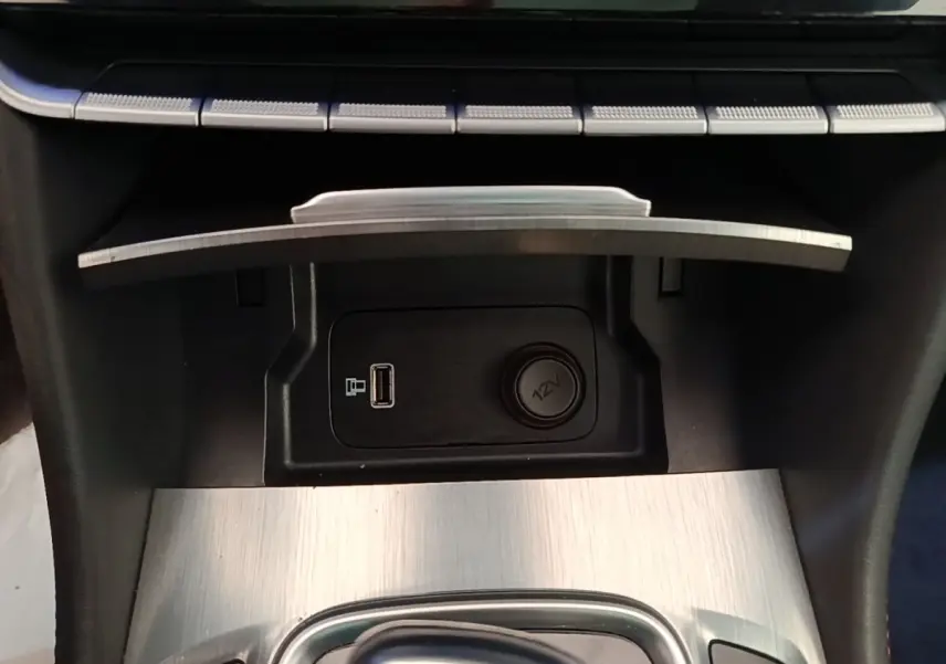 Gros plan sur la console centrale du MG Motor EHS 2023, montrant prise USB, prise 12V et finition aluminium brossé.