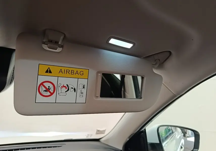 Détail intérieur du pare-soleil côté conducteur avec miroir et avertissement airbag dans un MG Motor EHS blanc.