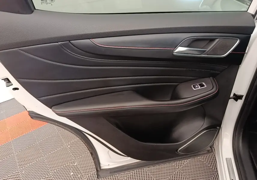 Vue intérieure côté gauche de la porte avant blanche du MG Motor EHS 2023 avec garniture noire et surpiqûres rouges.
