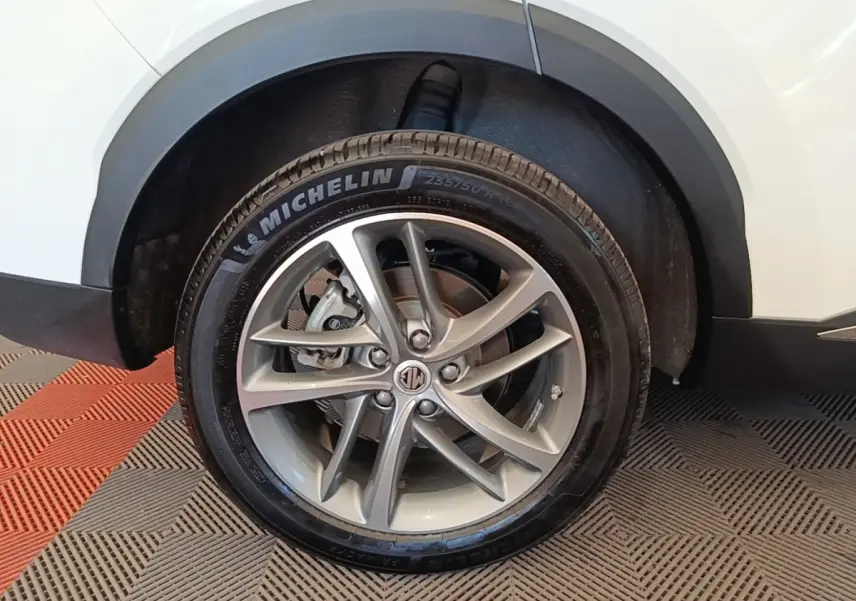 Gros plan sur la roue avant droite du MG MOTOR EHS blanc, avec jante alliage et pneu Michelin visible.