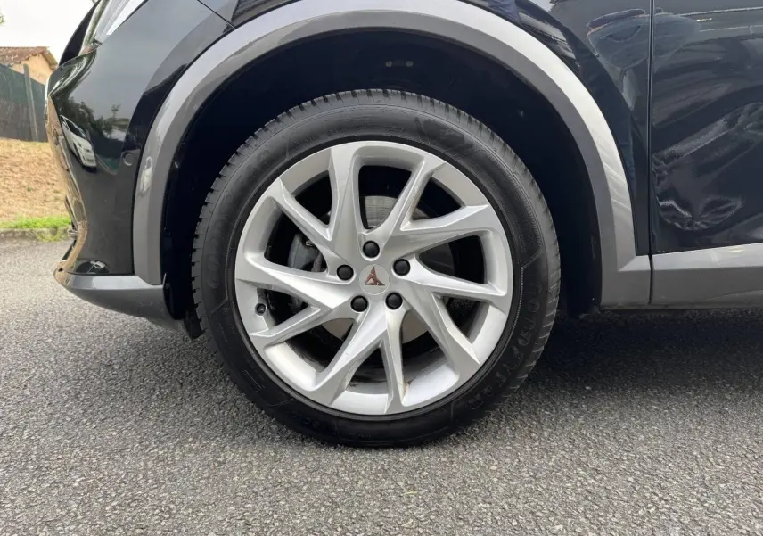 Gros plan sur la roue avant gauche avec jante alu argentée du CUPRA Formentor noir Minuit métallisé.