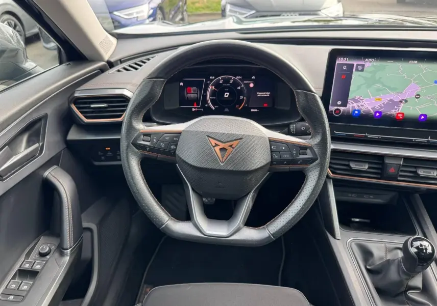 Vue intérieure centrée sur le volant sport noir et cuivre du CUPRA Formentor 2023 avec tableau de bord numérique et écran tactile GPS.
