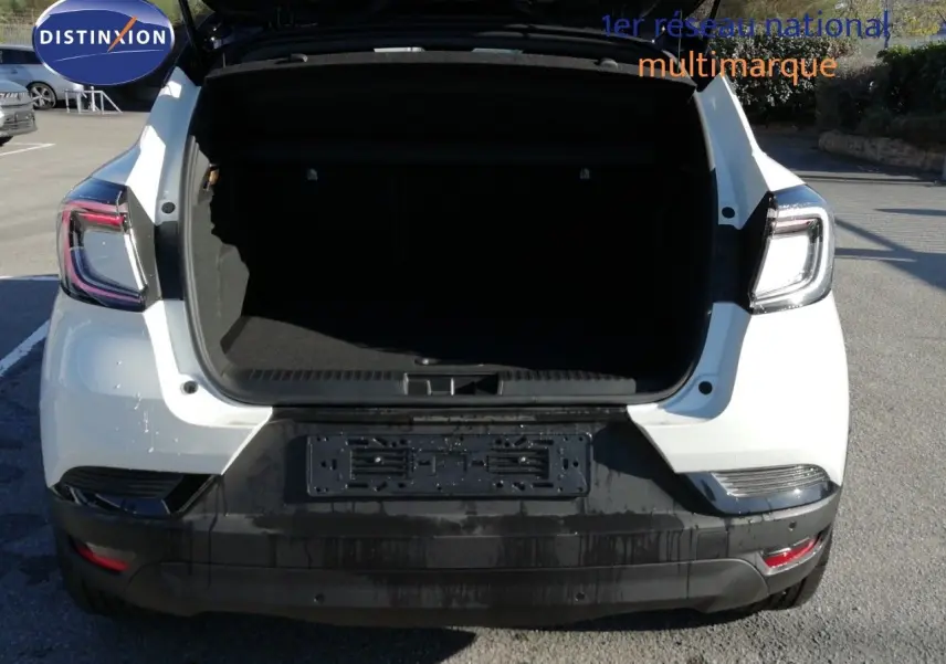 Vue arrière d’un Renault Captur blanc nacré avec coffre ouvert et toit noir visible, en extérieur sur parking.