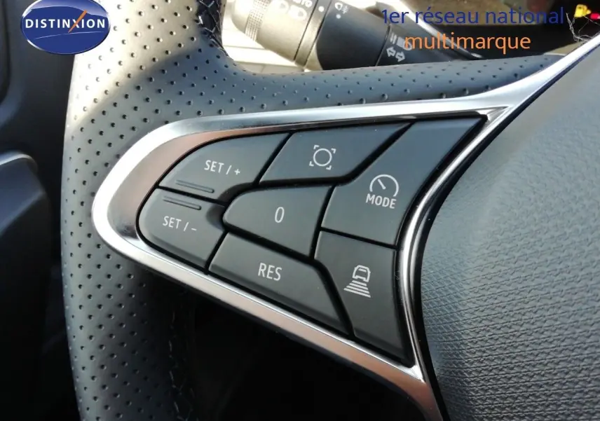 Gros plan sur les commandes au volant perforé du Renault Captur 2026, version hybride, avec finition noire et argentée.