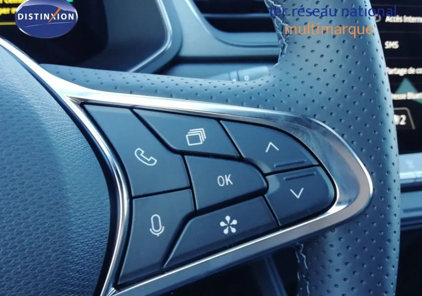 Gros plan sur les commandes multifonctions en cuir perforé du volant du Renault Captur blanc nacré 2026.
