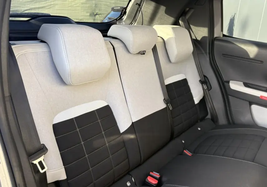 Vue intérieure des sièges arrière bi-coloris beige et noir de la Citroën C3 Turbo 100 Max, avec appuie-têtes et ceintures visibles.