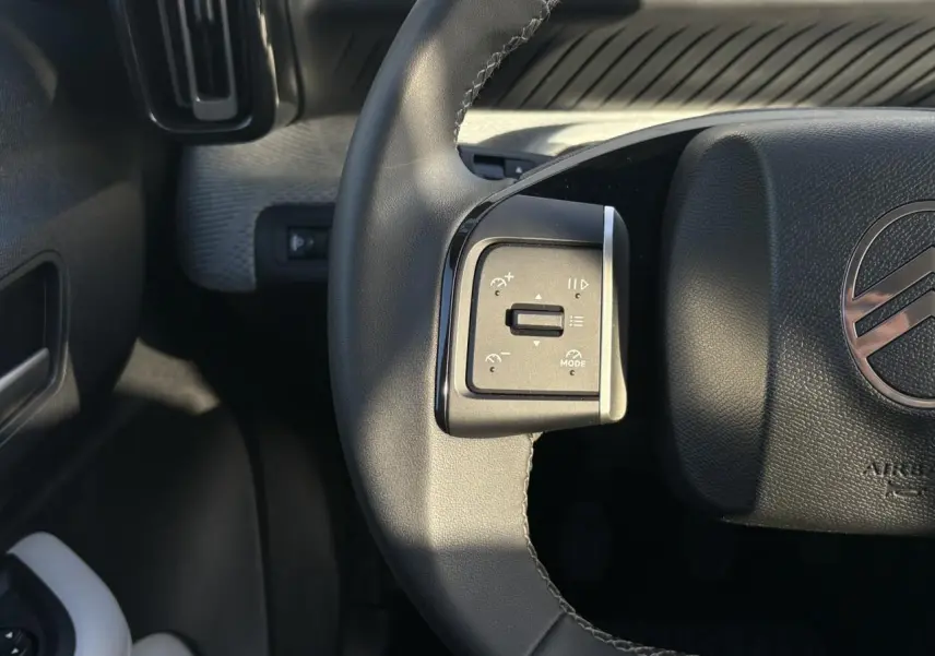 Gros plan sur la commande gauche du volant noir de la Citroën C3 Turbo 100 Max, avec logo Citroën visible.