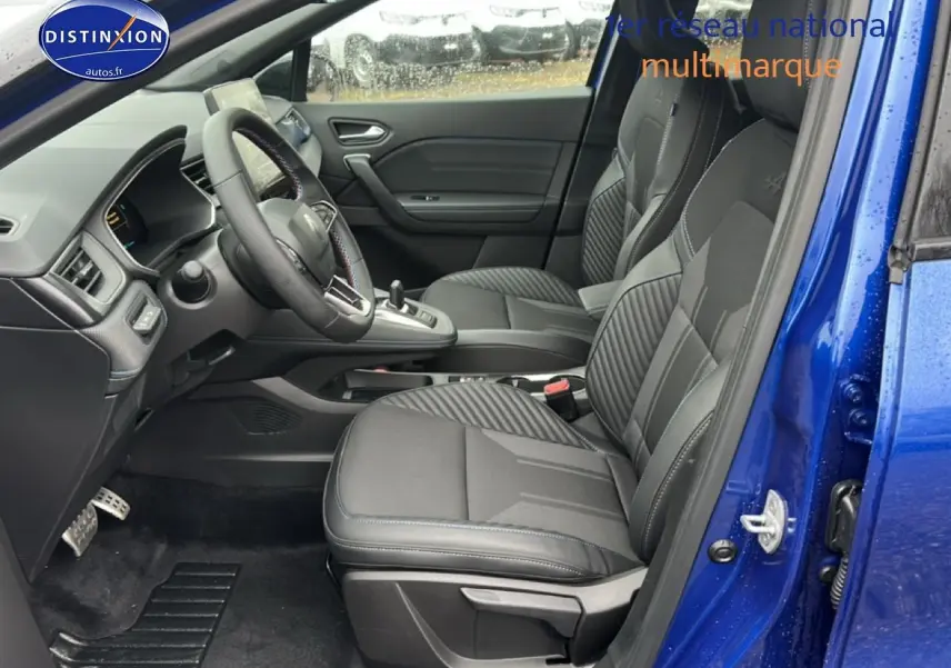 Vue intérieure côté conducteur du Renault Captur 2025 bleu iron, sièges sport noirs avec surpiqûres bleues et volant cuir multifonction.