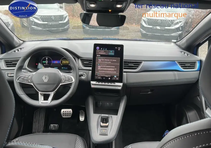 Vue intérieure avant du Renault Captur 2025 hybride, volant cuir, écran tactile vertical et finitions bleu iron t/noir.