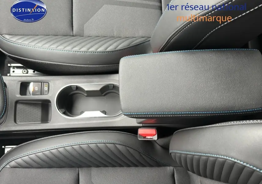 Gros plan sur l'accoudoir central noir avec surpiqûres bleues et porte-gobelets du Renault Captur 2025 intérieur.