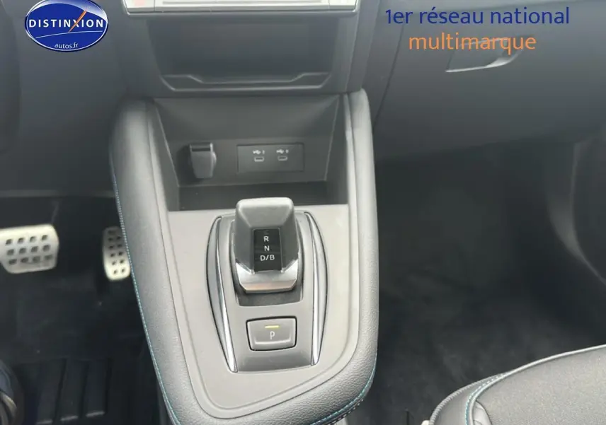 Vue plongeante sur la console centrale du Renault Captur 2025 hybride, avec levier de vitesse et surpiqûres bleues.