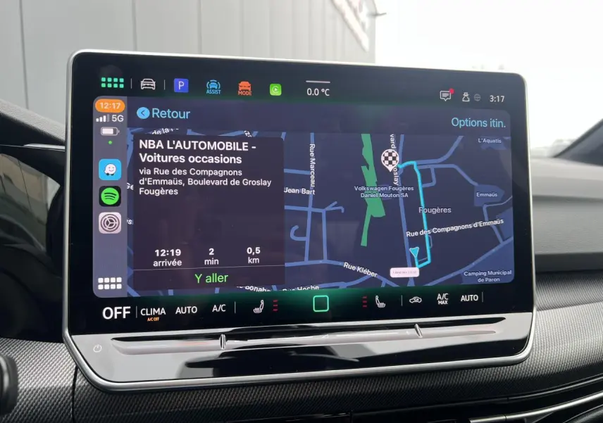 Écran tactile central de la Volkswagen Golf VIII noir, affichant la navigation avec carte et options climatisation.