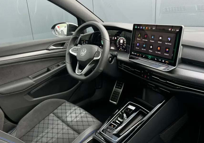 Vue intérieure côté conducteur de la Volkswagen Golf VIII R-Line avec tableau de bord numérique et écran tactile central.