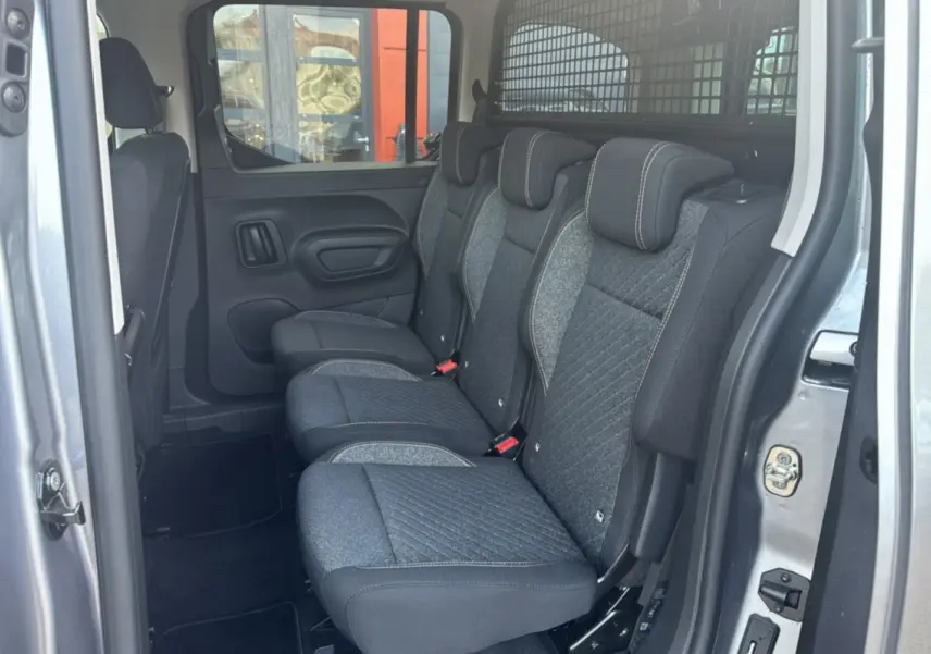 Vue intérieure côté droit des sièges arrière en tissu gris du Peugeot Rifter BlueHDi 130 Allure avec grille de séparation dans le coffre.