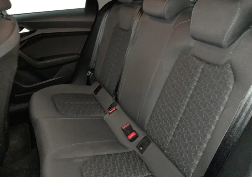 Vue intérieure côté conducteur de l'Audi A1 Sportback 2023, volant cuir noir, tableau de bord digital et levier de vitesse manuel.