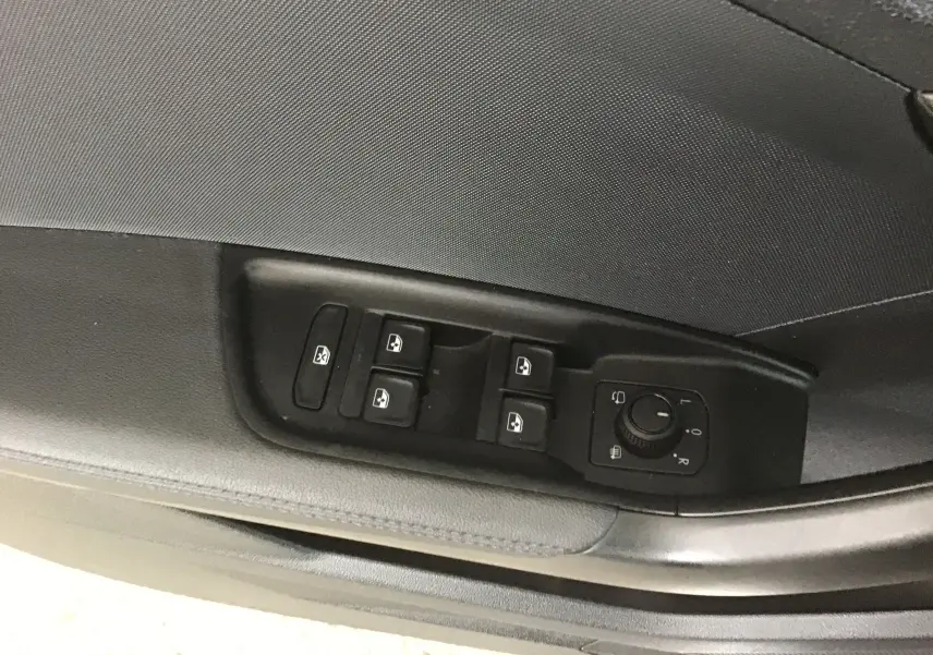 Vue rapprochée des commandes de lève-vitres et réglage des rétroviseurs côté conducteur de l'Audi A1 Sportback noir/gris 2023.