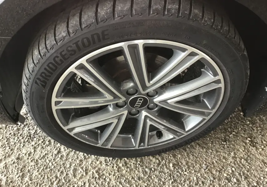 Gros plan sur la jante alliage 17 pouces gris et noir avec logo Audi au centre, montée sur pneu Bridgestone.