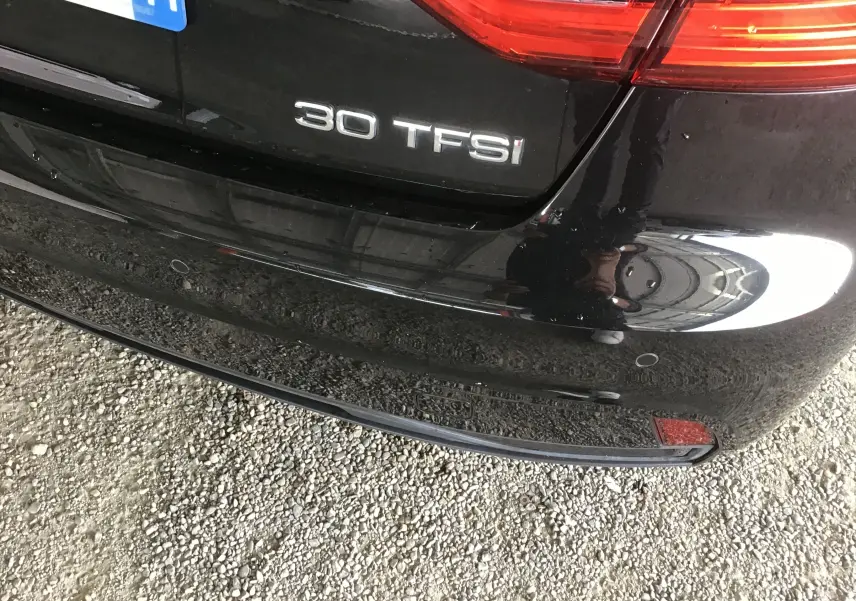 Gros plan sur le coffre arrière noir d’une Audi A1 Sportback 30 TFSI avec badge et feux arrière partiels visibles.