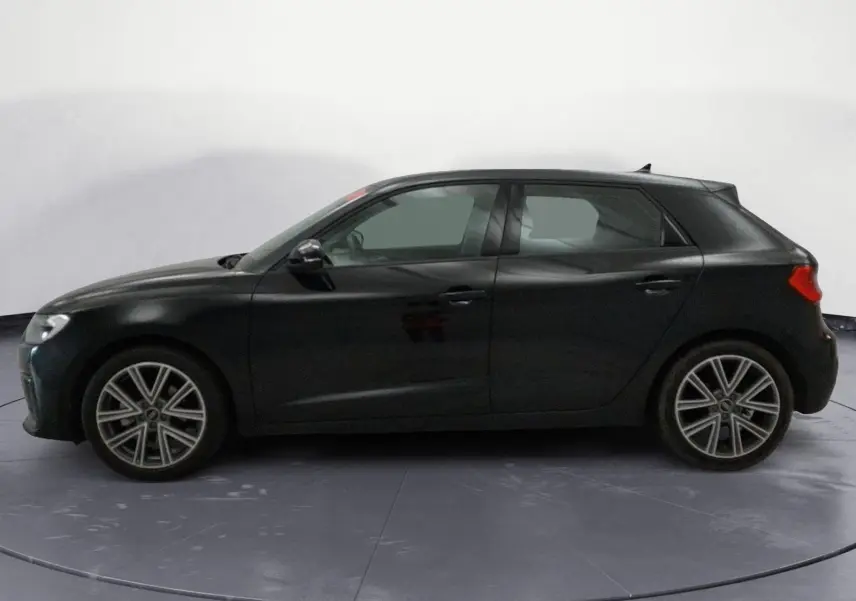 Vue intérieure côté conducteur de l'Audi A1 Sportback 2023, sièges sport noirs avec motifs hexagonaux et levier de vitesse manuel.