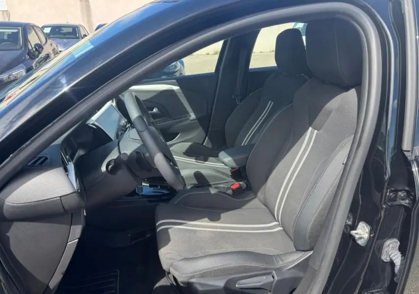 Vue intérieure côté conducteur d'une Opel Corsa noire 2025, sièges tissu avec bandes blanches et accoudoir central.