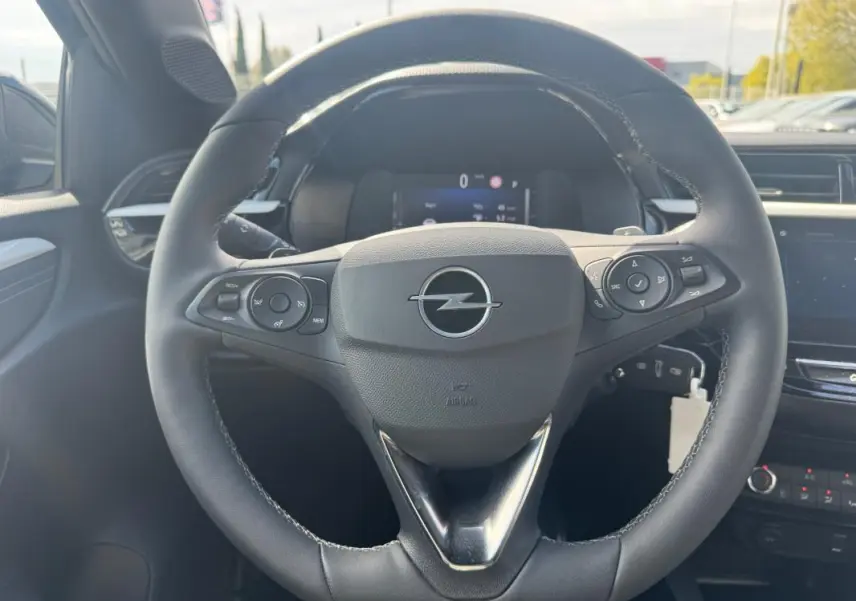 Vue rapprochée du volant noir multifonctions d’une Opel Corsa 2025 avec palettes au volant et tableau de bord numérique.
