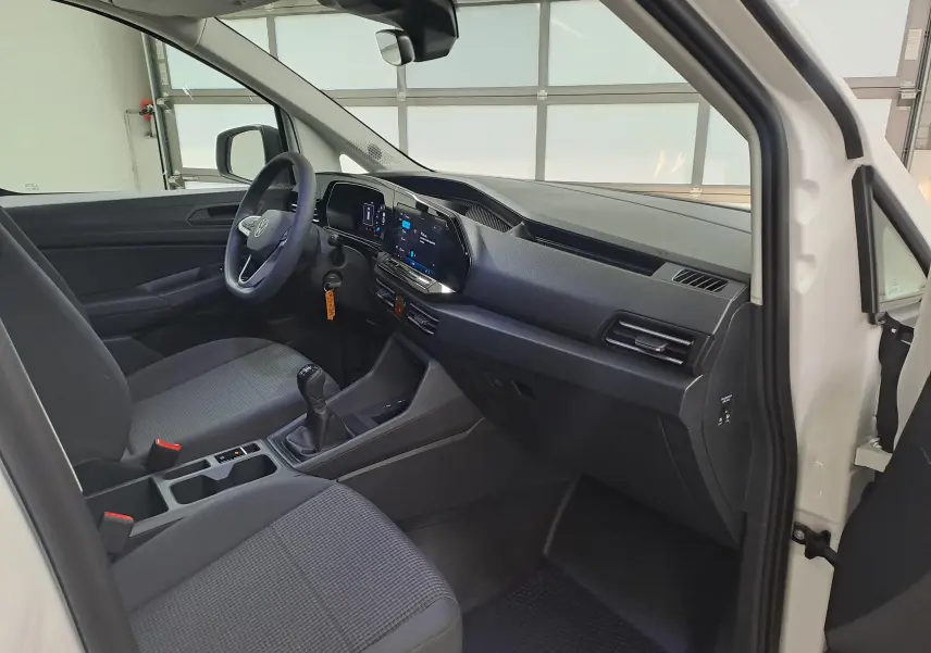 Vue intérieure côté conducteur du Volkswagen Caddy Cargo Maxi blanc candy 2026, avec tableau de bord numérique et boîte manuelle.