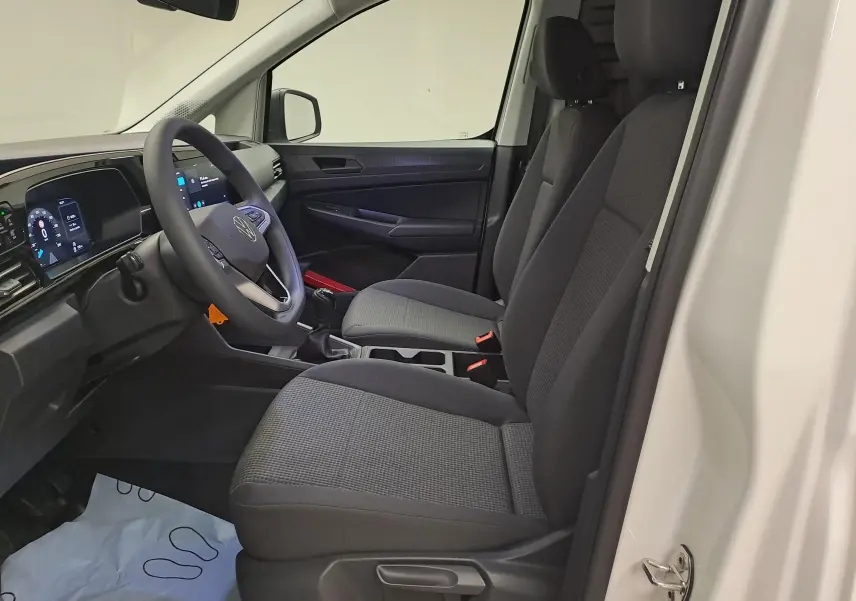 Intérieur côté conducteur du Volkswagen Caddy Cargo Maxi blanc, vue sur les sièges et le tableau de bord moderne.
