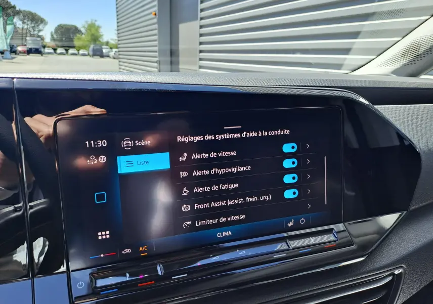 Vue rapprochée de l'écran tactile intérieur du Volkswagen Caddy Cargo Maxi blanc, affichant les réglages d'aide à la conduite.