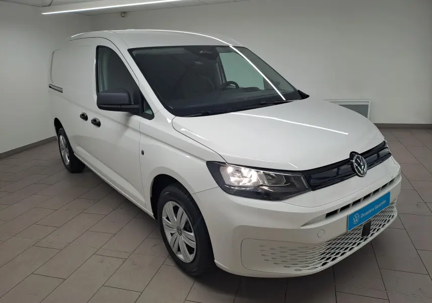 Volkswagen Caddy Cargo Maxi blanc candy vu en 3/4 avant droit, phare allumé et calandre noire brillante.