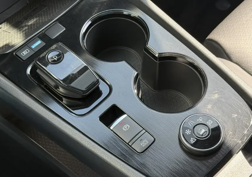 Gros plan sur la console centrale noire du Nissan X-TRAIL 2024 avec sélecteur de boîte auto et commandes de modes de conduite.