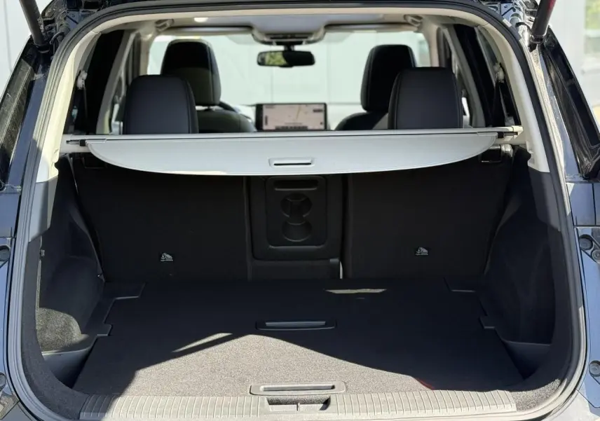 Coffre ouvert d’un Nissan X-TRAIL noir intense 2024, montrant l’espace de chargement avec cache-bagages déployé.