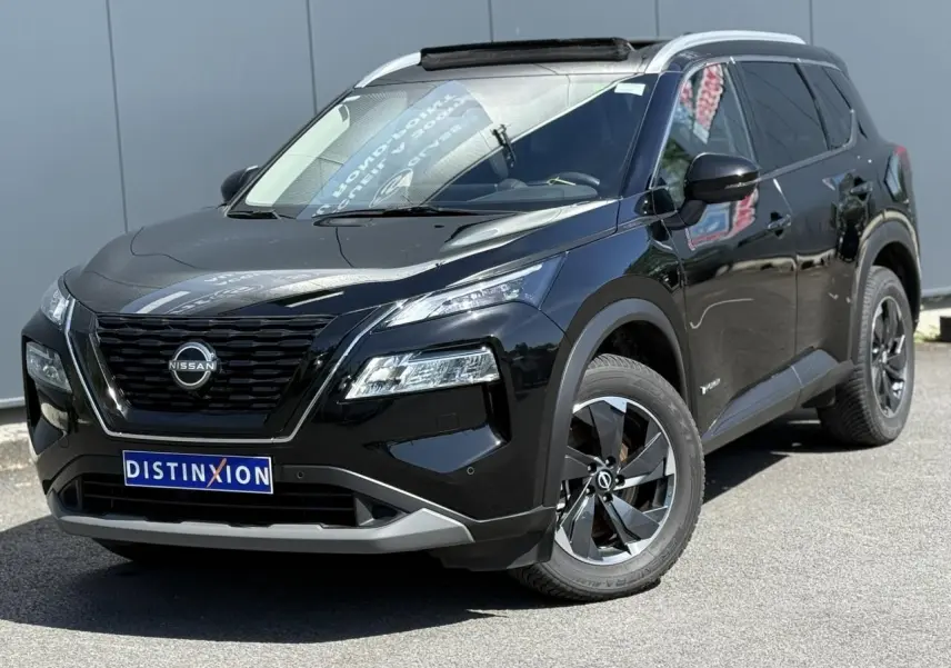 Nissan X-Trail 2024 noir intense en 3/4 avant droit, avec toit panoramique et jantes alliage noires.
