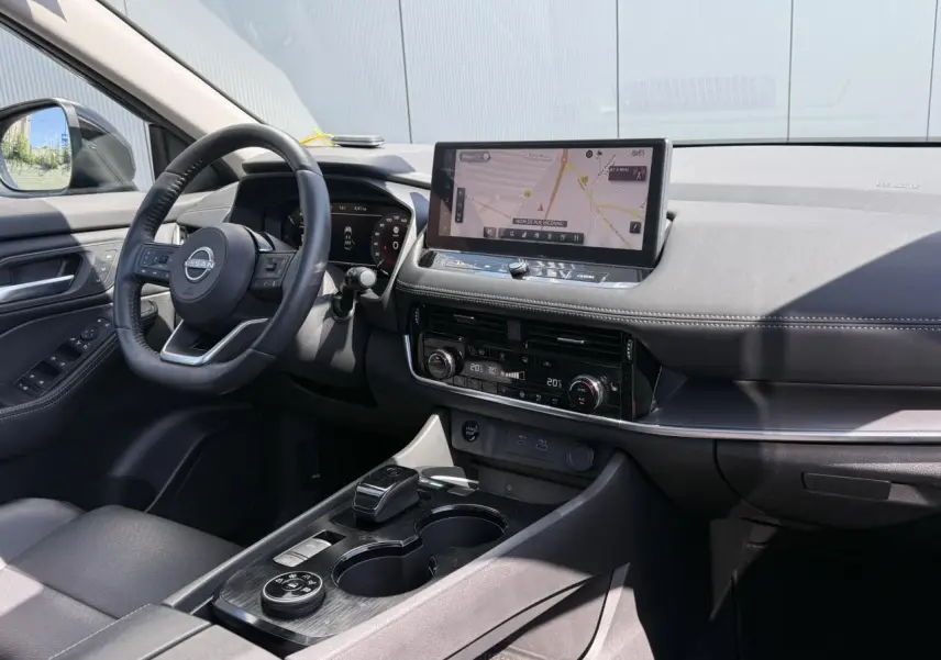 Vue intérieure côté conducteur du Nissan X-TRAIL 2024 noir intense, avec tableau de bord digital et écran tactile central.