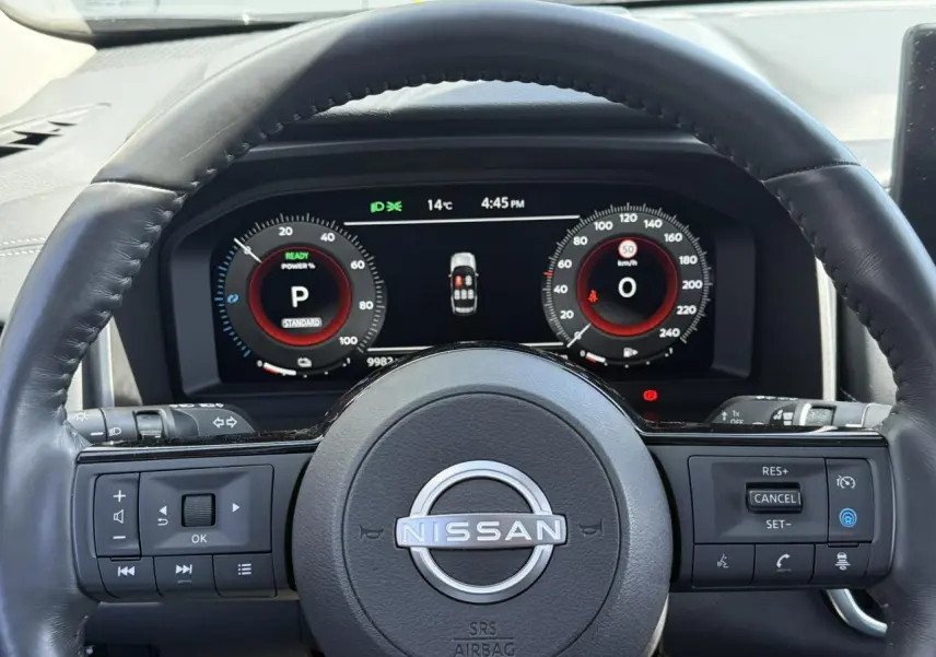 Vue intérieure centrée sur le volant cuir noir et le combiné d'instruments digital du Nissan X-TRAIL 2024.