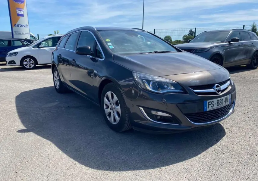 Opel Astra Sports Tourer gris vue 3/4 avant droit, phare LED et calandre chromée visibles, stationnée en extérieur.
