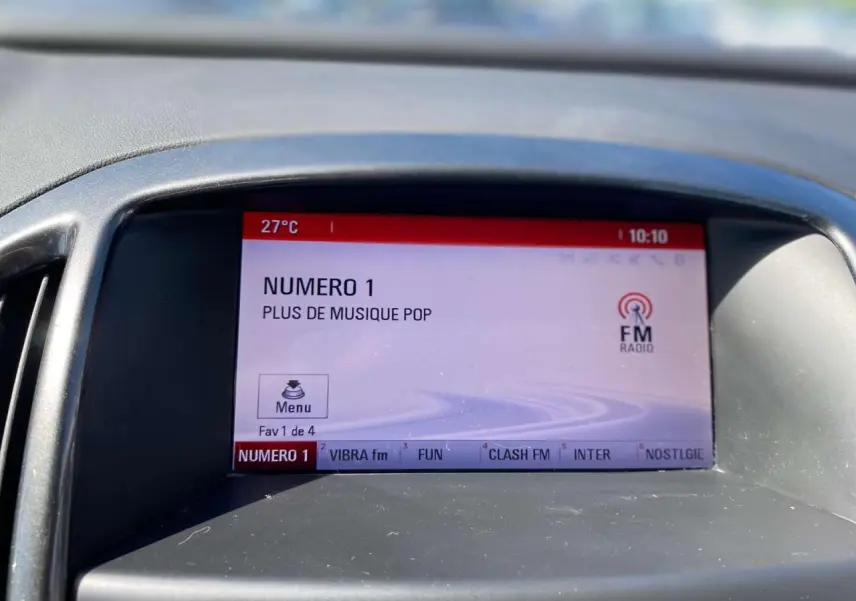 Écran central de l’Opel Astra Sports Tourer 2014 affichant la radio FM sur fond gris, vue de face rapprochée.