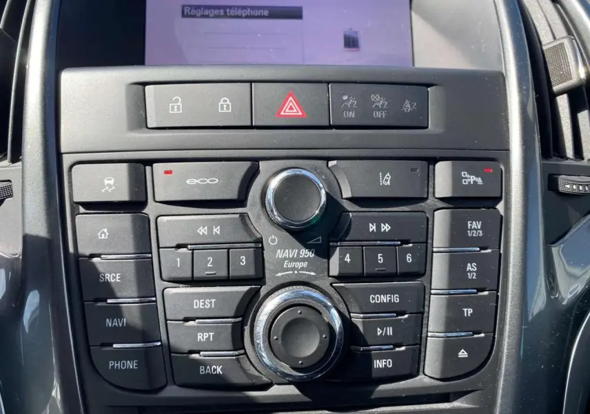 Gros plan sur la console centrale noire de l’Opel Astra Sports Tourer gris, montrant les boutons de navigation et commandes audio.
