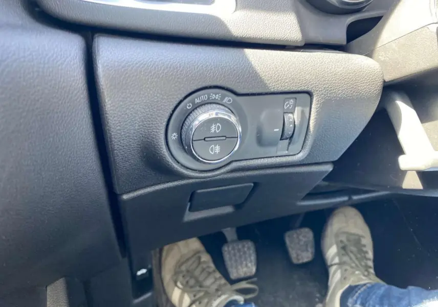 Gros plan sur le tableau de bord côté gauche de l'Opel Astra Sports Tourer gris, avec commandes des phares et pédales manuelles visibles.
