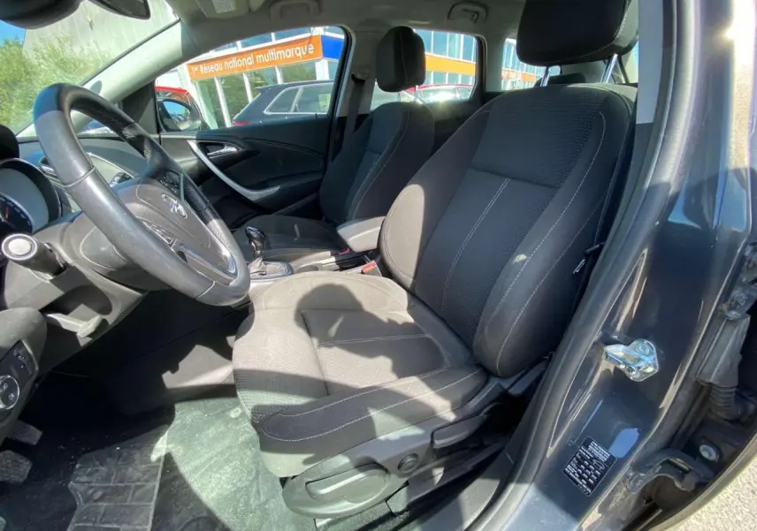 Vue intérieure côté conducteur de l’Opel Astra Sports Tourer gris, montrant les sièges et le volant en cuir.