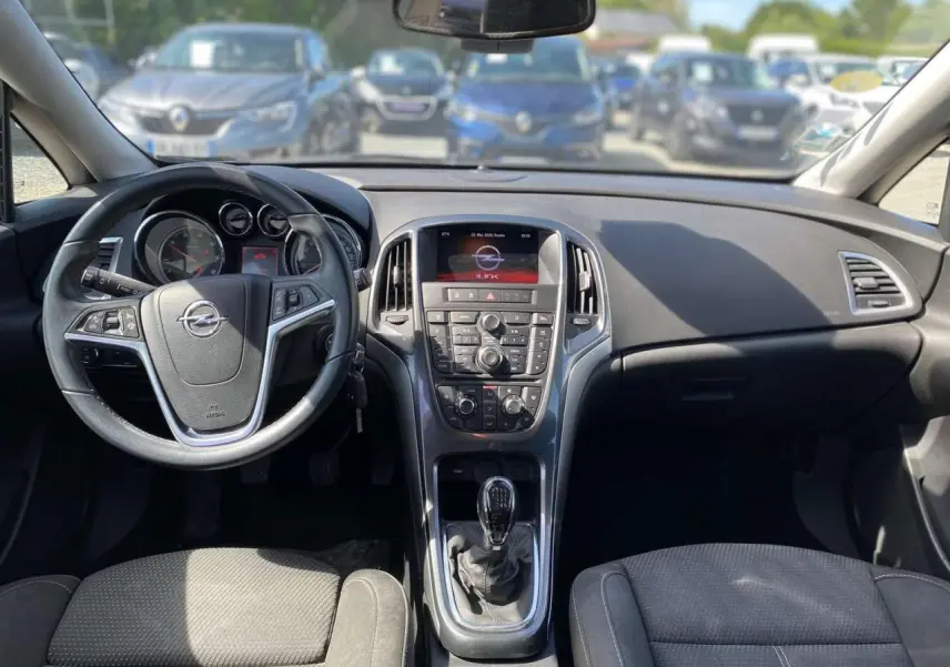 Vue intérieure avant de l'Opel Astra Sports Tourer 2014, tableau de bord gris avec volant multifonction et boîte manuelle.