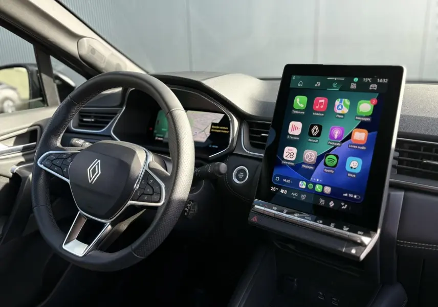 Vue intérieure du tableau de bord et volant noir du Renault Symbioz E-Tech avec écran tactile vertical allumé.
