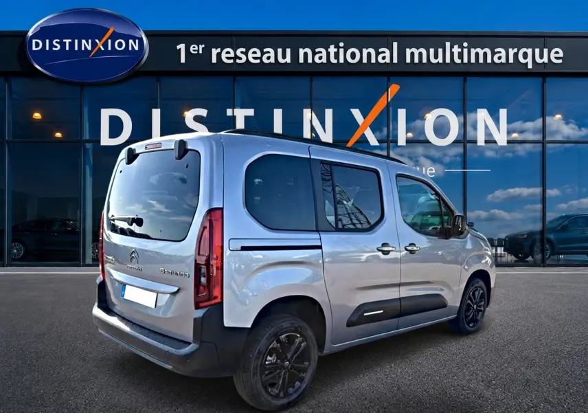 Vue 3/4 arrière droite d'un Citroën Berlingo Steel Grey 2026 avec barres de toit et jantes alu noires.