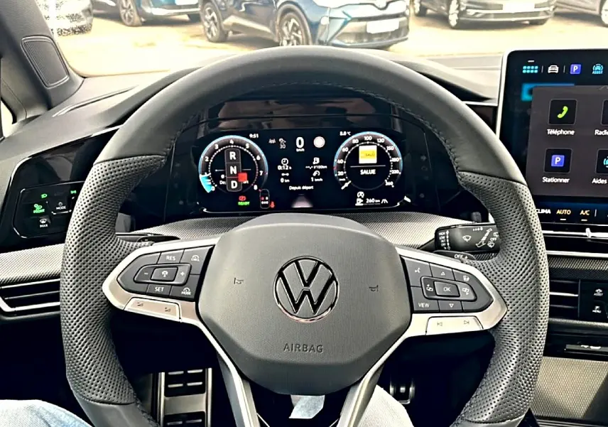 Vue intérieure centrée sur le volant cuir noir multifonction de la Volkswagen Golf 2026 avec tableau de bord numérique.